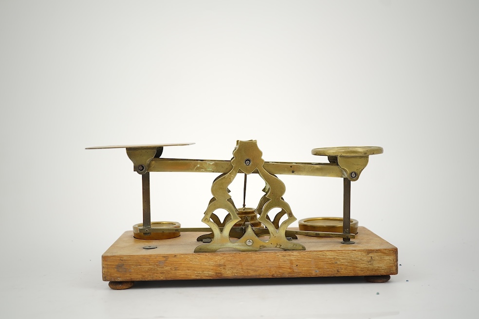 A Sampson Mordan & Co. set of brass postal scales on an oak base with weights, 27cm wide, with engraved prices for Inland Letter Post, etc.